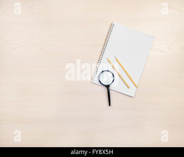 Lupe, Bleistifte und Notizblock auf leichte сoloured aus Holz Hintergrund. Stockfoto