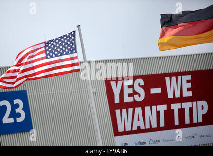 Hannover, Deutschland. 24. April 2016. A German (R) und ein US-nationalen Flagge auf dem Gelände der Hannovermesse, mit einem Banner, der liest "Ja - wir wollen TTIP" im Hintergrund, in Hannover, Deutschland, 24. April 2016 abgebildet. TTIP bezieht sich auf die transatlantische Handels- und Investitionspartnerschaft, eine vorgeschlagene Handelsabkommen zwischen der Europäischen Union (EU) und den Vereinigten Staaten. Die weltgrößten Industrie Messe Hannovermesse soll von US-Präsident Obama am selben Tag eröffnet werden. Foto: CHRISTIAN CHARISIUS/Dpa/Alamy Live News Stockfoto