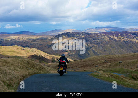 Mann auf dem Motorrad, der den Honister Pass (B5289), Lake District National Park, Cumbria, England, hinunterfährt Stockfoto