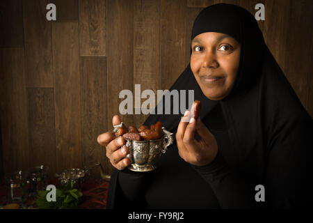 Afrikanische muslimische Frau in schwarzer Schleier präsentiert traditionelle süße Termine Stockfoto