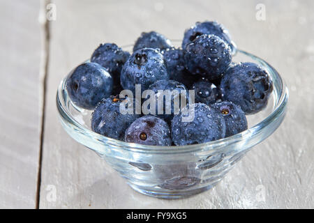 Frische Heidelbeeren mit Wasser Dropts in eine Glasschüssel auf einem weißen Tisch Stockfoto
