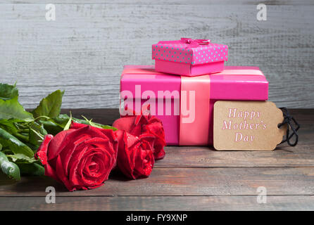 Glücklich Muttertag Text mit roten Rosen und Rosa Geschenk-Boxen auf Holztisch Stockfoto