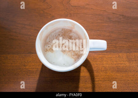 Naheinstellung von Draufsicht auf weiße Tasse heißen Mokkakaffee, erschöpft. Sie setzen auf braunen Holztisch und helles Licht kam fr Stockfoto