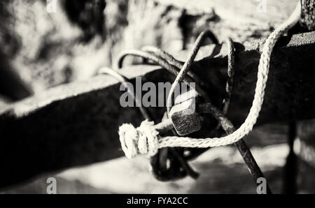 Nahaufnahme von einem rostigen Nagel, Schrott, Metall und weißen Seil in schwarz / weiß Monochrom Stockfoto