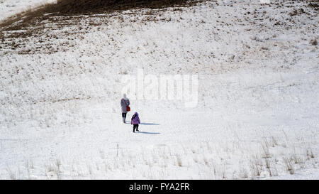 Frau und Kind weit weg in der Ferne zu Fuß über einen Schnee bedeckt Feld Stockfoto