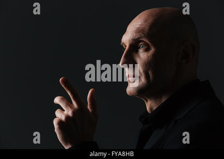 Nahaufnahme des schönen Boldheaded Geschäftsmann entfernt über schwarzem Hintergrund zeigend Stockfoto