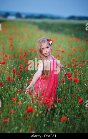 schöne Mädchen im roten Kleid geht im Mohnfeld Stockfoto