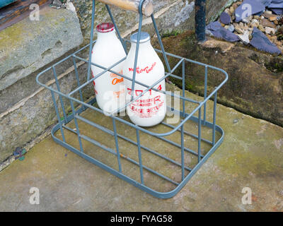 Zwei Flaschen frisch gelieferten Milch in einer Kiste auf einer Haustür in einem Yorkshire-Dorf Stockfoto
