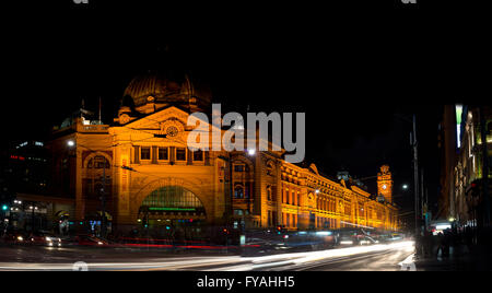 Ein Foto der Flinders Street Station mit den Linien der Lichter aus fahrenden Autos in der Nacht. Stockfoto