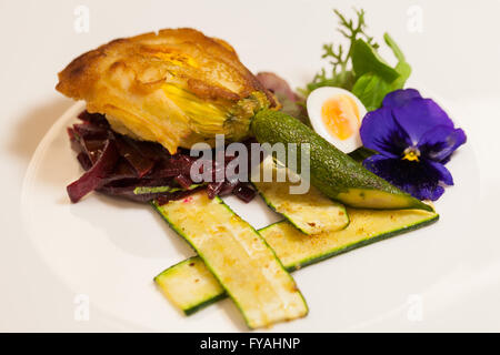 Köstliches Gourmet-Teller mit Biskuit Sandwich mit Rüben, Zucchini Streifen und Stiefmütterchen Garnitur über weißem Hintergrund Stockfoto