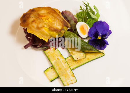 Köstliches Gourmet-Teller mit Biskuit Sandwich mit Rüben, Zucchini Streifen und Stiefmütterchen Garnitur über weißem Hintergrund Stockfoto