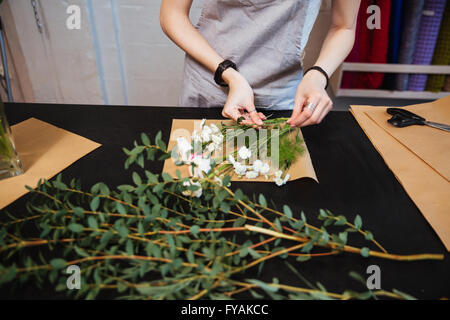 Draufsicht der Hände der jungen Frau Blumengeschäft Strauß mit weißen Blumen auf dem Tisch machen Stockfoto