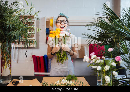 Blumenhändler glücklich erregte junge Frau mit Blumenstrauß stehen und Lachen im shop Stockfoto