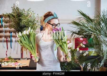 Glücklich schönen jungen Frau Floristen halten und riechen Tulpen im Blumenladen Stockfoto