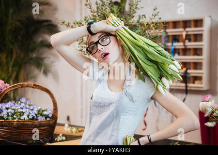 Hübsche junge Frau Floristen halten Rosenstrauss weisse Tulpen und im Blumenladen arbeiten erschöpft Stockfoto