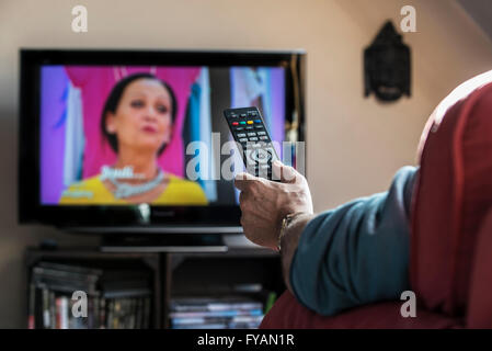 Mann in bequemen Stuhl Schaltkanäle mit Fernbedienung erfreulich Programm am Fernseher im Wohnzimmer suchen Stockfoto