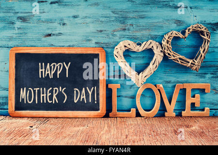 der Text happy Muttertag in einer Tafel geschrieben neben einigen Holzbuchstaben bilden das Wort Liebe und einige rustikale Hand platziert Stockfoto