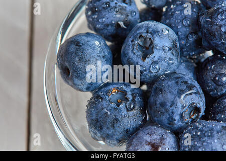 Frische Heidelbeeren mit Wasser Dropts in eine Glasschüssel auf einem weißen Tisch Stockfoto