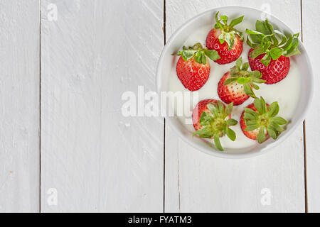Smoothie-Schüssel mit Strasberries im weißen Joghurt auf einem weißen Holztisch Stockfoto