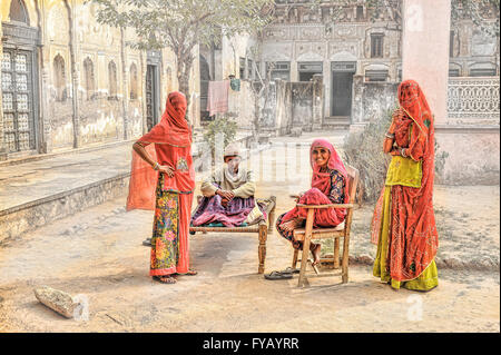 Drei Frauen in regionaler Tracht warten mit ihrem Vater in einem Fatehpur Haveli Innenhof, typischen Rajasthani-Szene Stockfoto