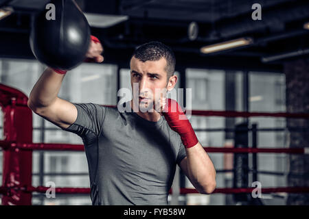 Männlicher Boxer mit einem Boxsack im Fitness-Studio Stockfoto