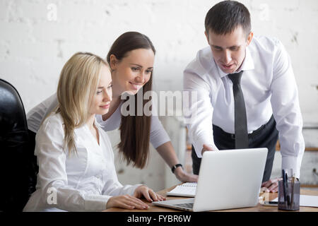 Teamarbeit-Konzept. Gruppe von drei lächelnde junge Menschen am Projekt am Schreibtisch arbeiten. Business-Team in formalen tragen mit comp Stockfoto