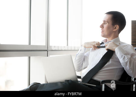 Porträt von fröhlichen hübscher junger Geschäftsmann sitzt in seinem Büro entspannen nach der Arbeit auf Laptop-computer Stockfoto