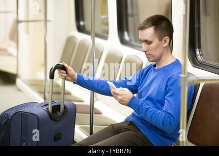 Porträt von schönen jungen Mann casual-Style Kleidung sitzt auf dem Stuhl in der u-Bahn mit smartphone Stockfoto