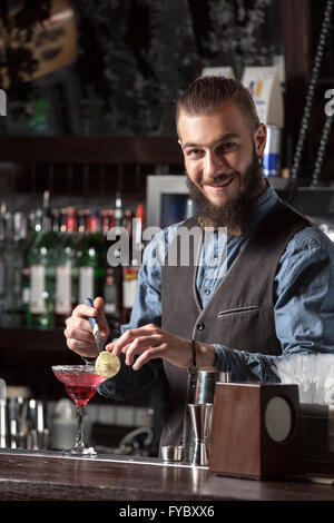 Glückliche junge Barkeeper cocktail an der Bar serviert. Stockfoto