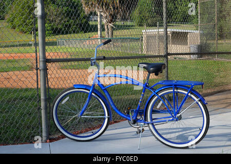 Klassischen Stil American Cruiser-Fahrrad geparkt vor einem Junior League Baseball Grouns und Einbaum, April 2016 Stockfoto