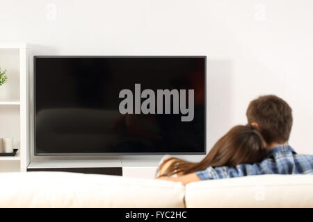 Rückansicht eines Paares vor dem Fernseher in einer Couch zu Hause. Leerer Bildschirm-Ansicht Stockfoto