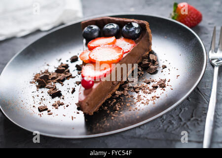 Leckere Schoko-Mousse Torte auf einem Teller dekoriert mit frischen Erdbeeren, Heidelbeeren und Preiselbeeren Stockfoto