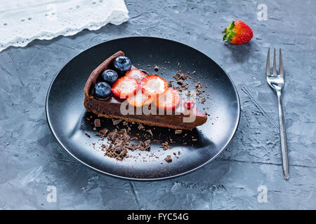 Leckere Schoko-Mousse Torte auf einem Teller dekoriert mit frischen Erdbeeren, Heidelbeeren und Preiselbeeren Stockfoto