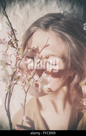 Schöne junge Frau, die duftenden Blumen auf dem Baum Stockfoto