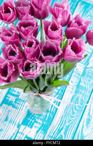 violette Tulpen auf dem blauen Hintergrund aus Holz. Stockfoto