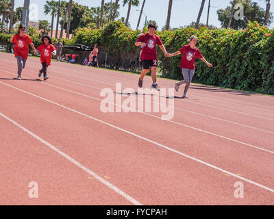 Erwachsenen Helfer Hilfe Behinderte Kinderrennen im 50-Meter-Lauf bei der Southern California Special Olympics statt in Santa Barbara, Kalifornien. Stockfoto