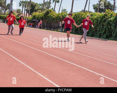 Erwachsenen Helfer Hilfe Behinderte Kinderrennen im 50-Meter-Lauf bei der Southern California Special Olympics statt in Santa Barbara, Kalifornien. Stockfoto