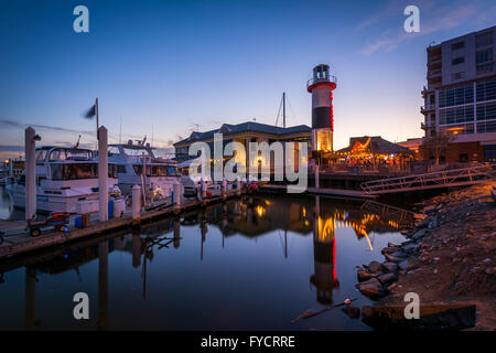 Leuchtturm und Boote entlang der Uferpromenade in der Dämmerung, im Kanton, Baltimore, Maryland. Stockfoto