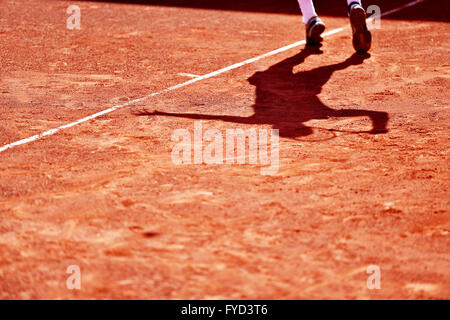 Schatten ein Tennis-Spieler in Aktion auf einem Sandplatz Stockfoto