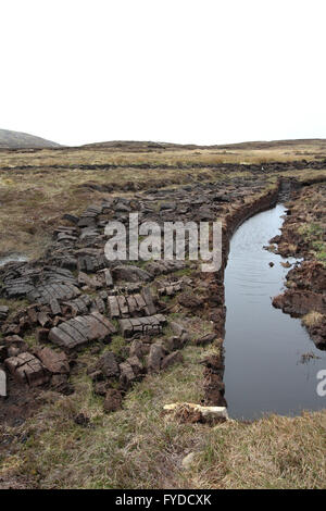 Moor- und Torfschnitte stapelten sich auf Moorflächen neben einem Wasserlauf auf Arramore - der größten bewohnten Insel im County Donegal Ireland. Stockfoto