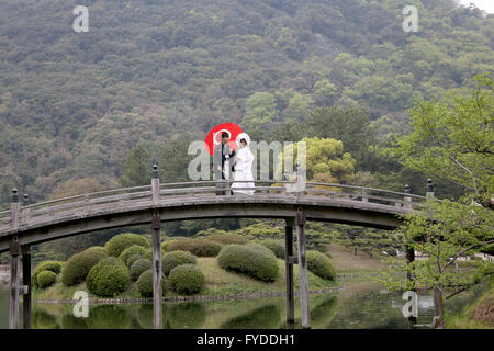 Japanische Hochzeitspaar in traditionellen Kimono gekleidet stehen Holzbrücke am japanischen Garten Stockfoto