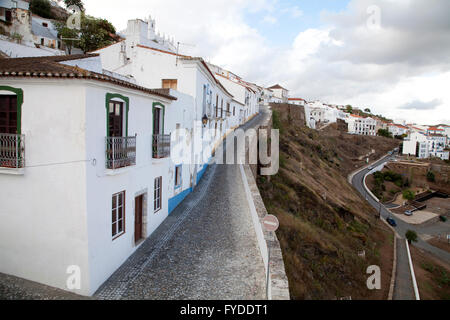 Häuser entlang der gepflasterten Straße entlang der Stadtmauer der alten maurischen Stadt von Mértola, Portugal. Stockfoto