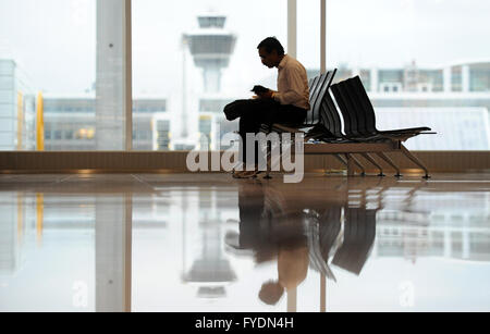 München, Deutschland. 26. April 2016. Ein Passagier sitzt an einem Tor das Satellitenterminal am ersten Tag seines Bestehens am Flughafen in München, 26. April 2016, mit dem Turm im Hintergrund abgebildet. Foto: ANDREAS GEBERT/Dpa/Alamy Live-Nachrichten Stockfoto