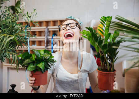 Gerne hübsche junge Frau Blumengeschäft Pflanzen in Blumentöpfen und lachen Stockfoto