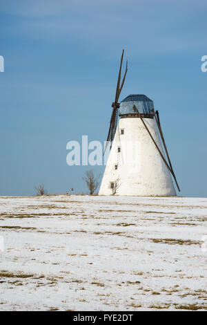 Alte Windmühle stehend im verschneiten Winter-Zeit-Feld gegen blauen Himmel Stockfoto