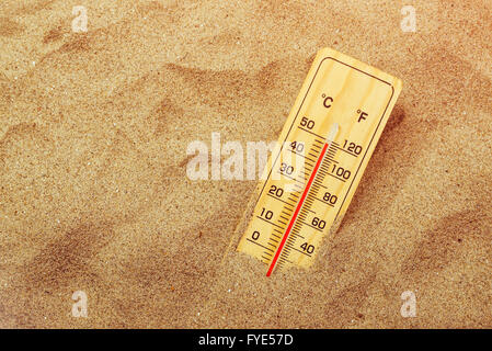 Thermometer mit Celsius und Fahrenheit Skala auf warmen Strandsand mit Datensatz extrem hohen Temperaturen Stockfoto