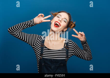 Glücklich süße junge Frau, die mit Peace-Zeichen Stockfoto