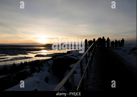 Silhouetten von Touristen, die den Winter-Sonnenaufgang in der sehr beliebten Thingvellir (Þingvellir) Nationalpark in Island zu beobachten Stockfoto