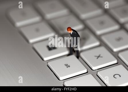 Eine Miniatur Figur Geschäftsmann stehend auf einer Laptoptastatur Stockfoto