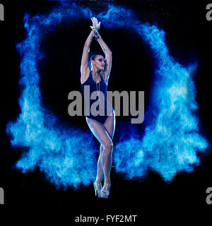 Junge Frau in blauen Pulverwolke auf schwarzem Hintergrund springen Stockfoto